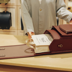 ブラウンのランドセルを開いて荷物を入れる様子